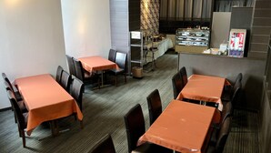 A restaurant with multiple tables and chairs, a counter with a display case, and a Coca-Cola vending machine. - APA Hotel Hachioji Eki Nishi (Hachioji)