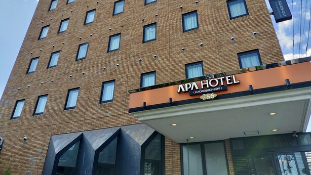 A multi-story hotel with a modern brick facade, a prominent sign for APA HOTEL, and a series of windows. - APA Hotel Hachioji Eki Nishi (Hachioji)