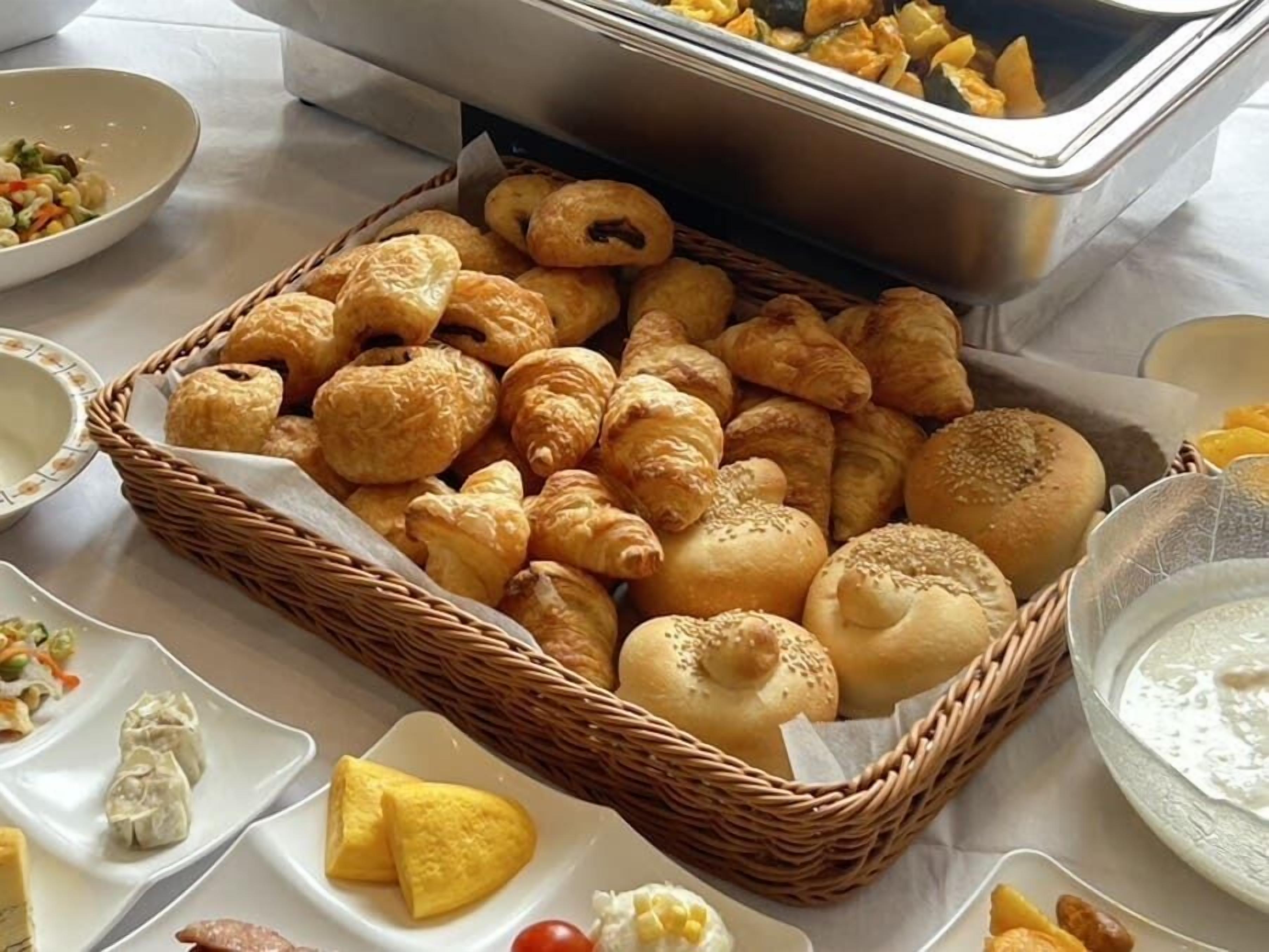 Una mesa de buffet con una variedad de productos horneados, incluyendo croissants, panes y pastelería.