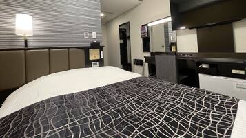 Une chambre d’hôtel équipée d’un lit, d’un bureau, d’une chaise, d’un miroir et d’un radiateur fixé au mur.