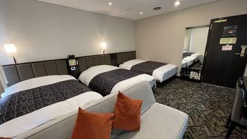 Ein Hotelzimmer mit drei Betten, einem großen Spiegel und Teppichboden.