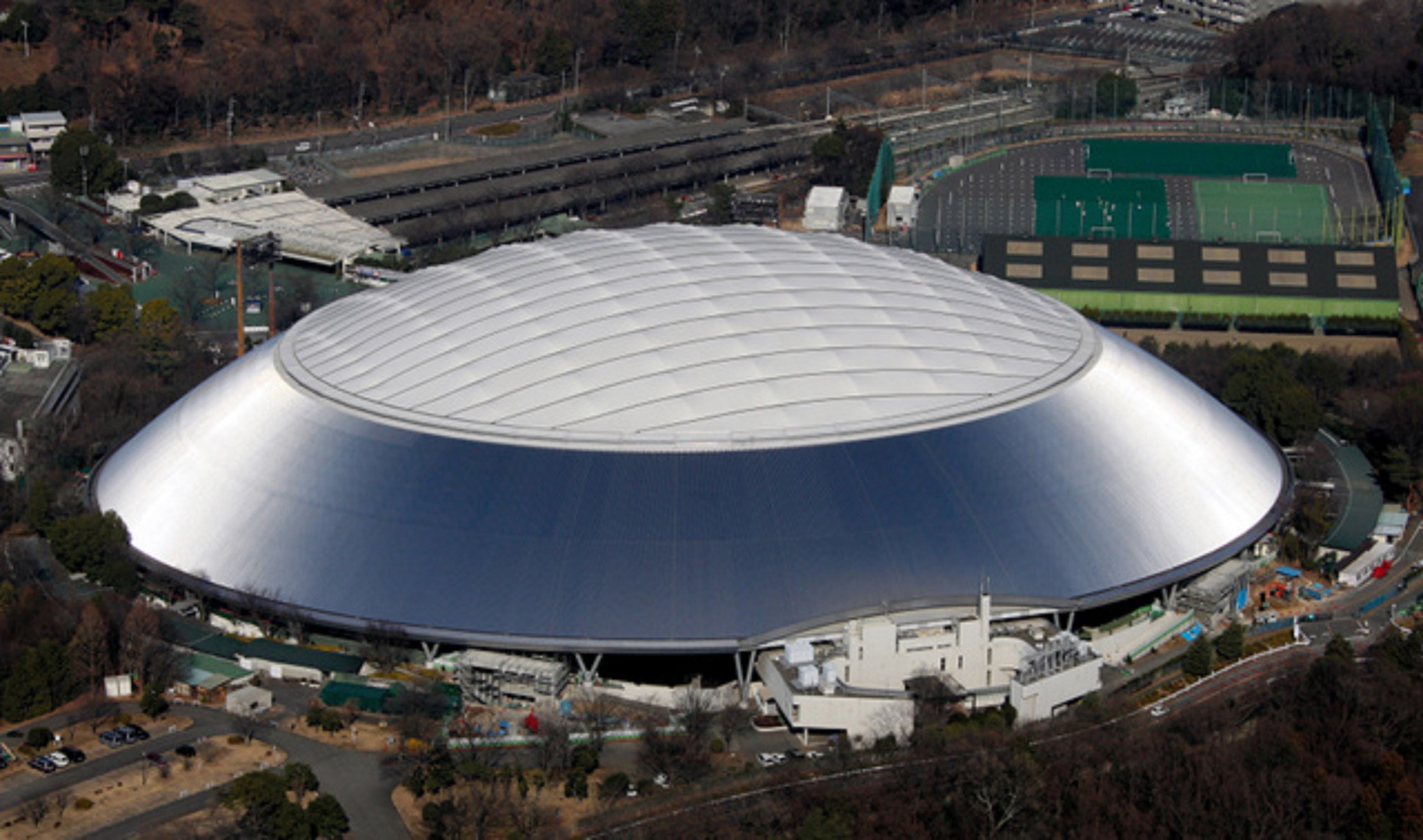 A large, modern stadium with a distinctive dome roof, surrounded by parking areas and roads.