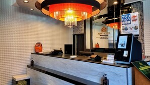 A hotel reception area with a marble counter, a modern chandelier, and a digital information kiosk. - APA Hotel Hachioji Eki Nishi (Hachioji)