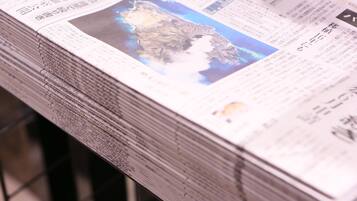 A stack of newspapers with a map and text on the front page.