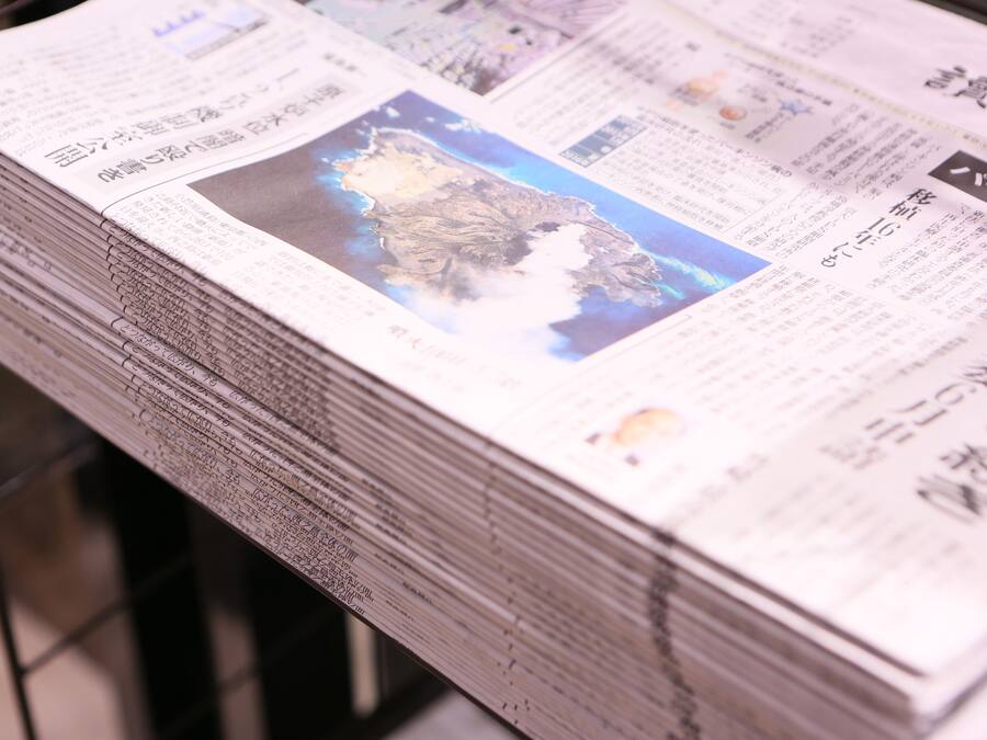 A stack of newspapers with a map and text on the front page.