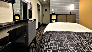 A hotel room with a bed, a desk, a chair, a mirror, a clock, and a door. - APA Hotel Hachioji Eki Nishi (Hachioji)