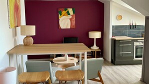 Ett kompakt bostadsutrymme med en matplats, ett litet kök och en sittgrupp med ett litet bord och stolar.