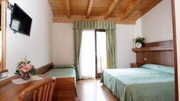 A room with two beds, a wooden ceiling, a TV mounted on the wall, and a window with curtains.