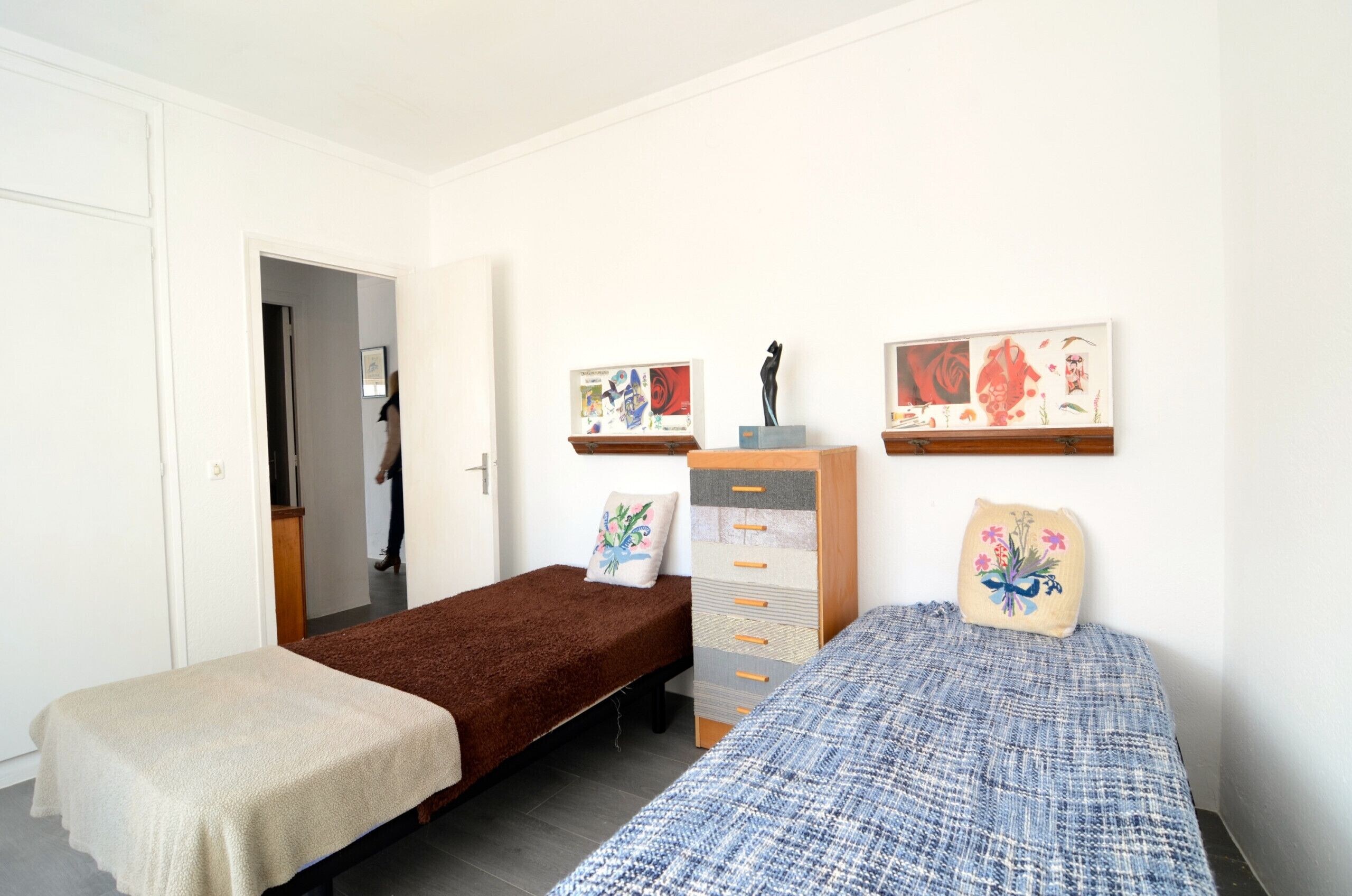 Ein kleines, sauberes Zimmer mit zwei Einzelbetten, einem Holzkapitänsbett und Bildern an der Wand.