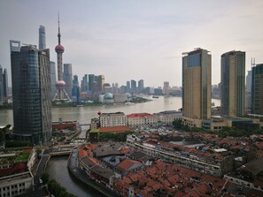 A cityscape with modern skyscrapers, a historic tower, and a river. - Shanghai The Bund View Guesthouse (Shanghai)