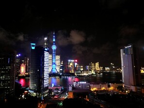 A nighttime cityscape with illuminated buildings and a prominent tower with a blue-lit spire. - Shanghai The Bund View Guesthouse (Shanghai)