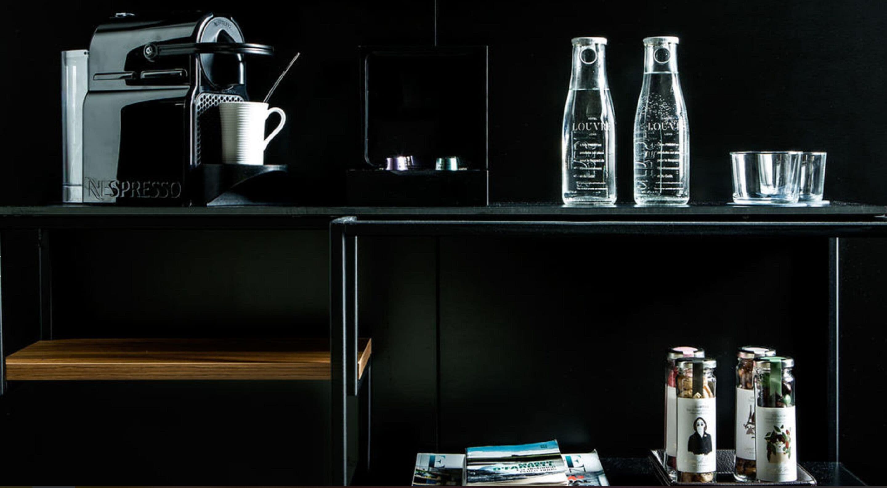 Eine moderne Küche mit einer Kaffeemaschine, zwei Glasflaschen und einigen Gläsern auf der Arbeitsplatte.