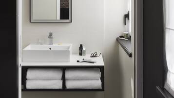A bathroom with a white sink, mirror, and black and white patterned floor tiles.