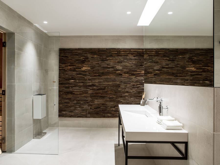 A modern bathroom with a glass shower enclosure, a large mirror, and a white sink with a towel rack.