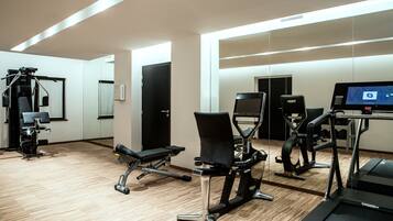 A gym with exercise equipment, a treadmill, and a mirror.