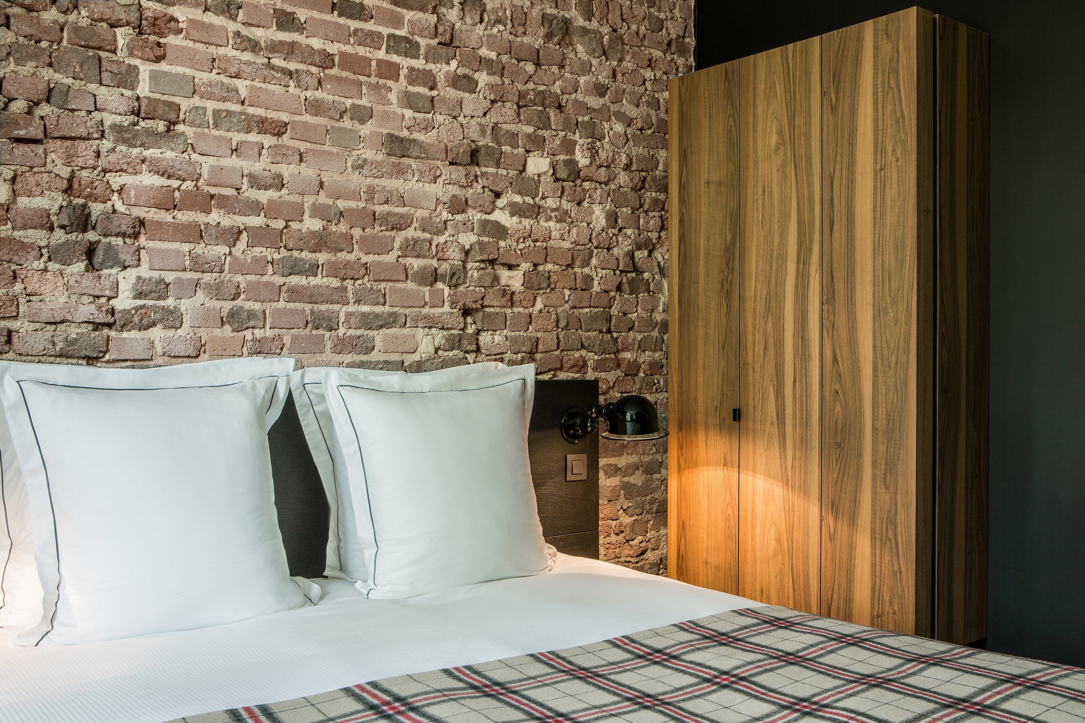 Ein Schlafzimmer mit Backsteinwand, einem Holzschrank und einem Bett mit weißen Kissen.