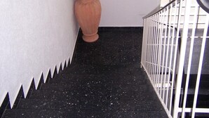 A hallway with a black marble floor, a large terracotta vase, and a framed painting on the wall. - Hotel Post (Kelkheim)