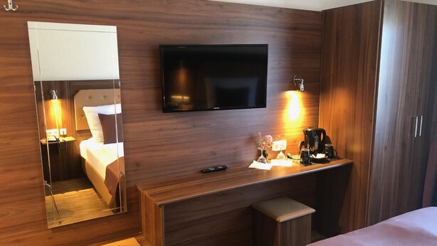 A hotel room with a bed, a desk with a mirror, a television, and a coffee maker. - Hotel Post (Kelkheim)