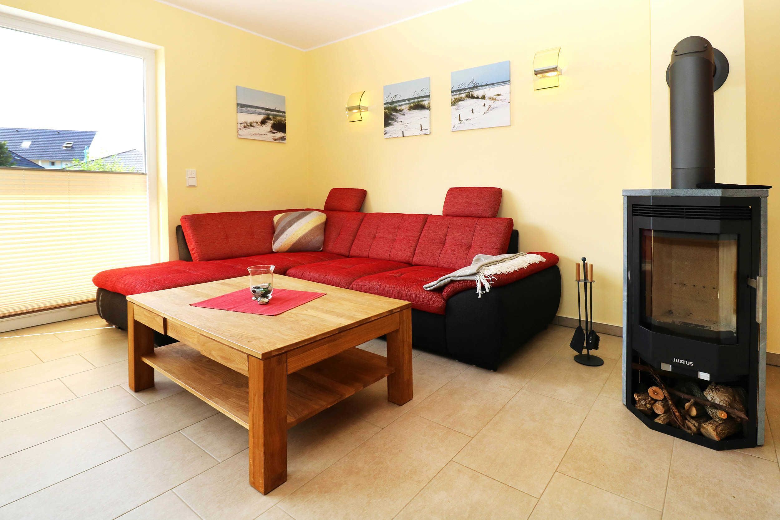 A living room with a red sofa, a wooden coffee table, and a wood-burning stove.