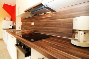 A modern kitchen with a wooden countertop, a built-in microwave, and a coffee maker.