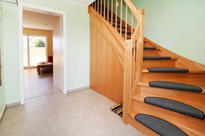 A wooden staircase with a handrail and carpeted steps leading to a room with a door.