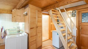 A wooden interior with a kitchen, a wooden staircase, and a door with a frosted glass panel. - Ferienwohnung 'Hühnerstall' an der Nordsee (Stadland)
