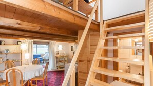 A wooden interior with a dining area, a staircase, and a view of the outdoors. - Ferienwohnung 'Hühnerstall' an der Nordsee (Stadland)