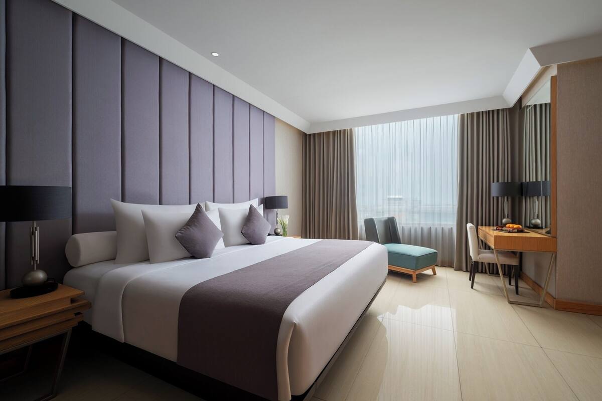 Ein modernes Hotelzimmer mit einem großen Bett, einem Schreibtisch und einem Stuhl.