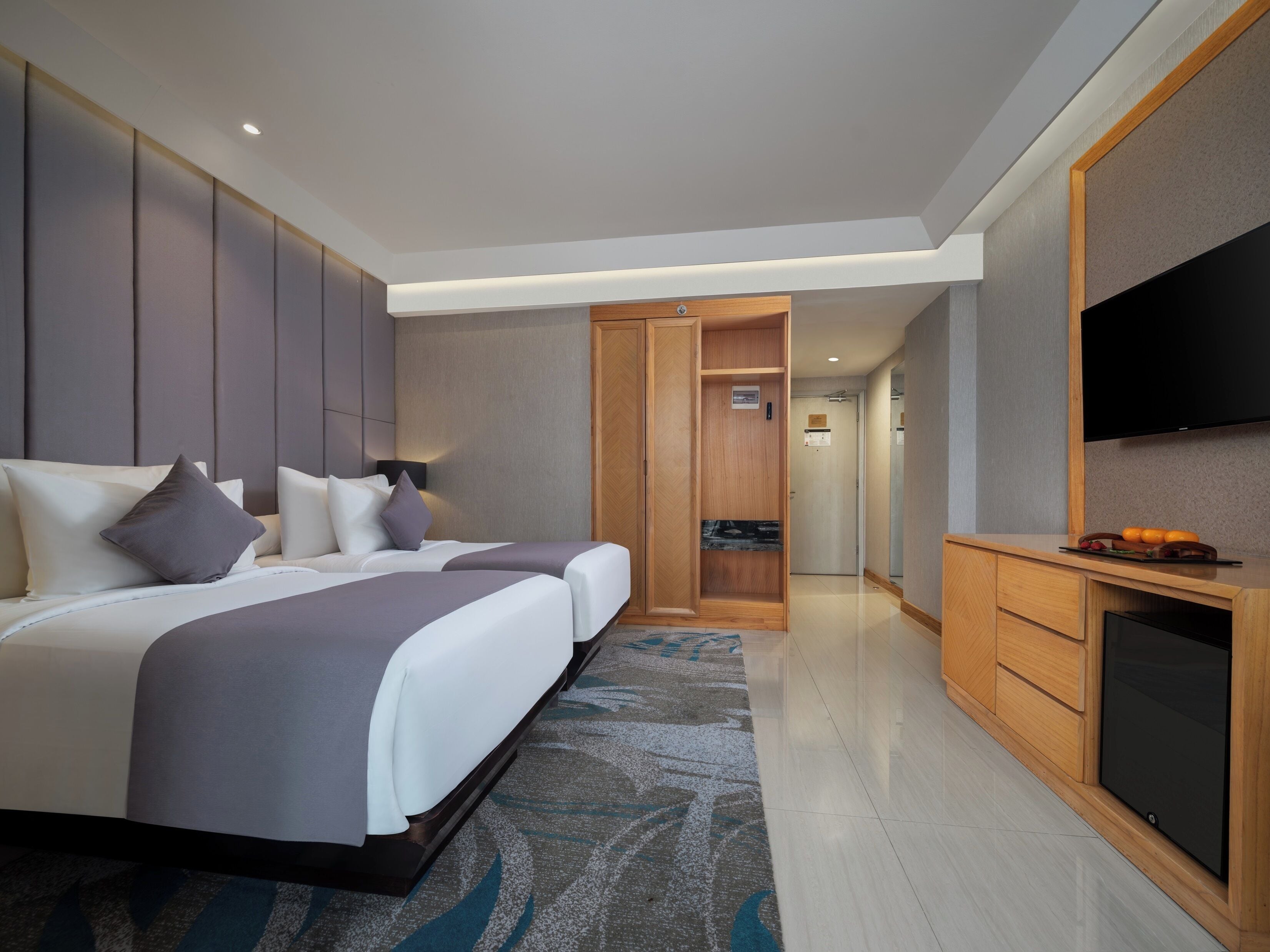 Quarto de hotel com uma cama, televisão, escrivaninha e casa de banho visível através de uma porta aberta.