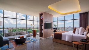 Una habitación de hotel moderna con una amplia vista de la ciudad, un sofá, una cama, un televisor y una mesa de centro.
