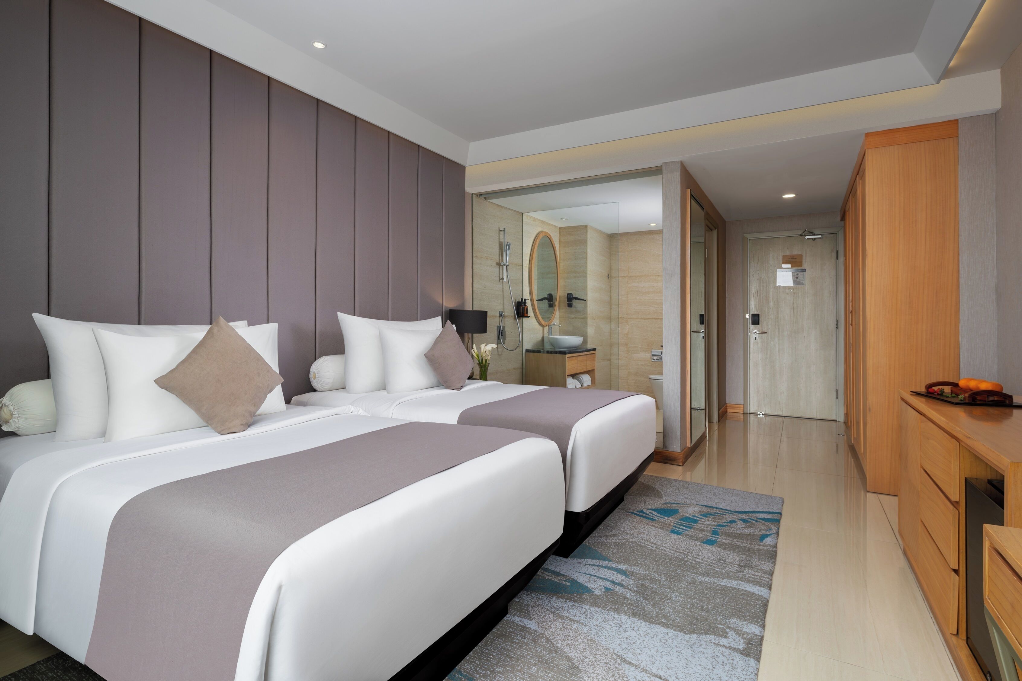 Een moderne hotelkamer met twee bedden, een badkamer met spiegel en een houten bureau.