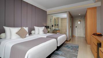 Een moderne hotelkamer met twee bedden, een badkamer met spiegel en een houten bureau.