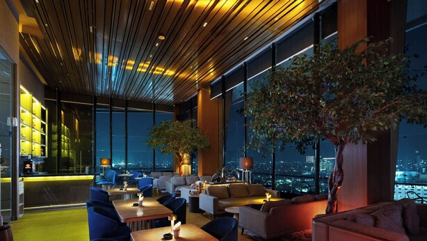Un salón moderno con vista a la ciudad, techo de madera y asientos cómodos.