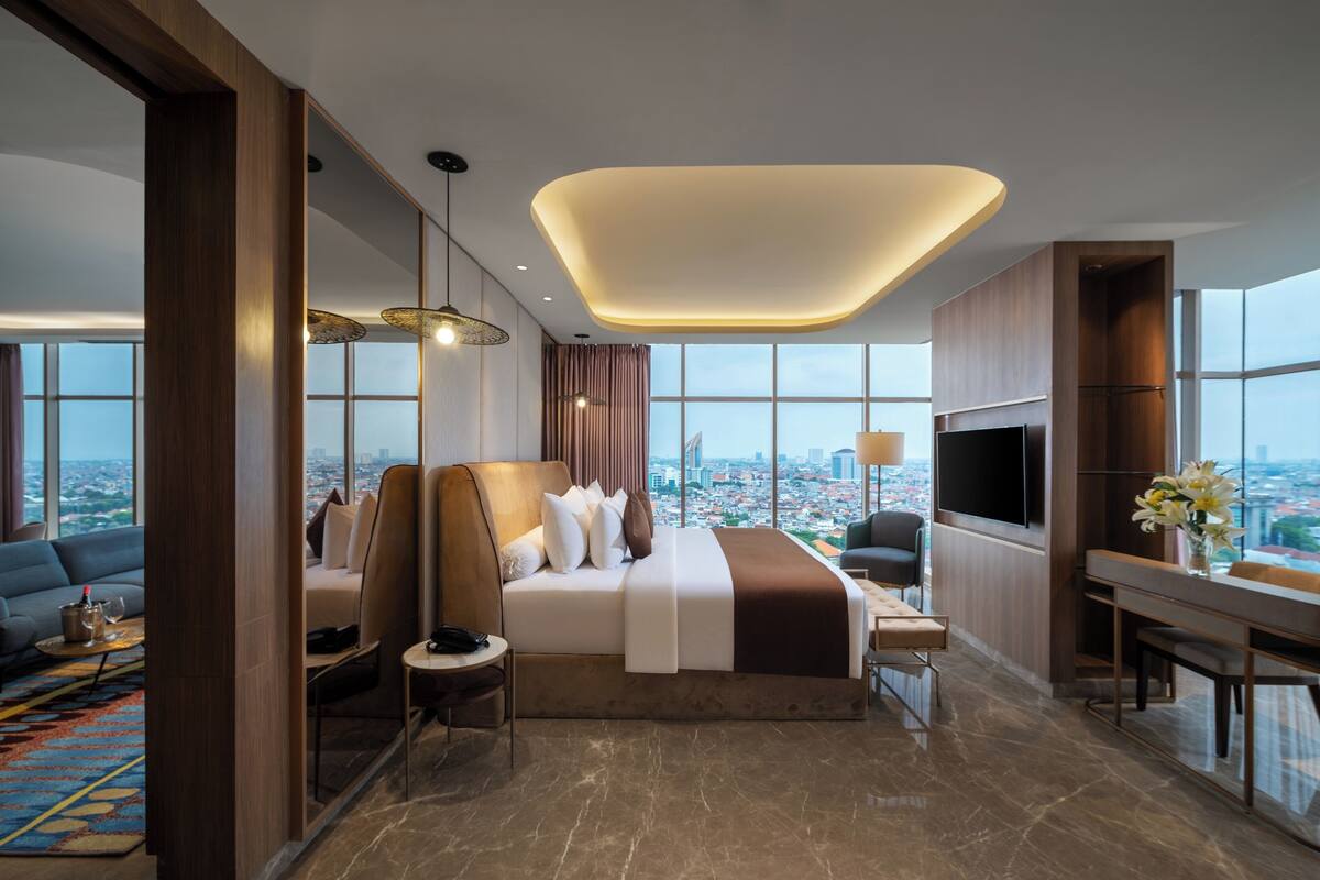 Ein modernes Hotelzimmer mit einem großen Bett, einer Couch, einem Schreibtisch und einem Fernseher.