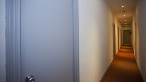 Un pasillo con una puerta cerrada, piso alfombrado e iluminación empotrada.