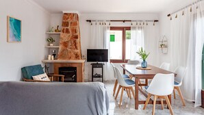 Una sala de estar con chimenea, televisor, una mesa de comedor con sillas y un sofá.