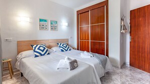 Habitación de hotel con dos camas, cabeceros de madera, ropa de cama blanca y un armario de madera.