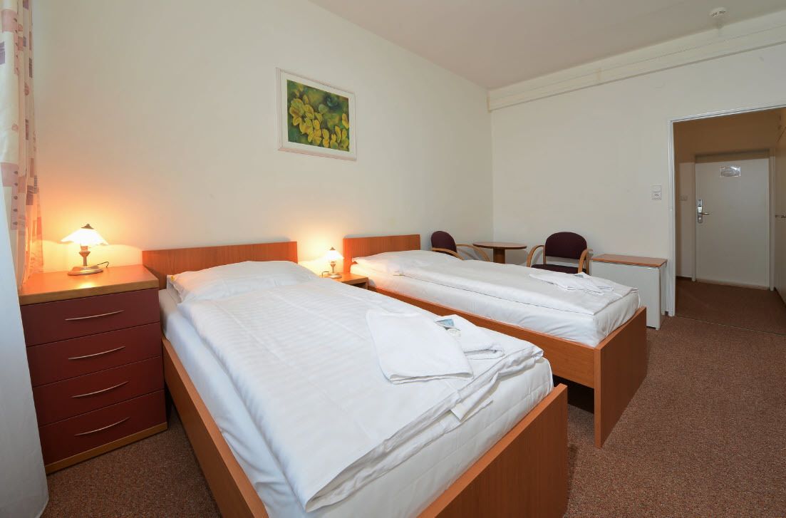 Une chambre d’hôtel avec deux lits simples, un bureau, une chaise et une petite table.