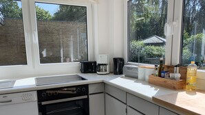 Eine moderne Küche mit Geschirrspüler von Bosch, einer Kaffeemaschine und einem Toaster. Fenster bieten Blick ins Freie.