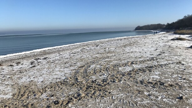 Ein Strand mit felsigem Ufer und freiem Blick auf das Meer.