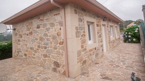 A stone building with a sloped roof, a small porch, and a stone pathway leading to the entrance. - Casa de Piedra Playa de Estorde con vistas al mar (Cee)