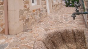 A stone building with a stone fountain in the foreground. - Casa de Piedra Playa de Estorde con vistas al mar (Cee)
