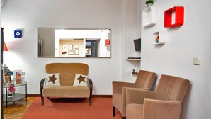 A room with a sofa, two armchairs, a red carpet, a mirror, and a small red shelf. - Hostal Los Alpes (Madrid)