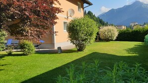 A well-maintained garden with a lawn, a variety of shrubs, and a building with a satellite dish.