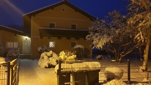 A two-story house with a snow-covered front yard and a metal gate.