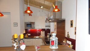A modern kitchen with a wooden countertop, a microwave, a sink, and a stove. There are two pendant lights hanging above the counter.