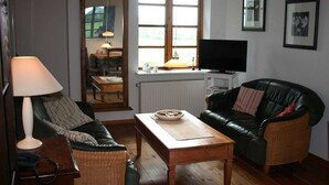 A living room with a sofa, a coffee table, a television, and a lamp.