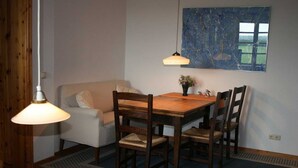 A dining area with a wooden table and chairs, a white sofa, and two pendant lights.