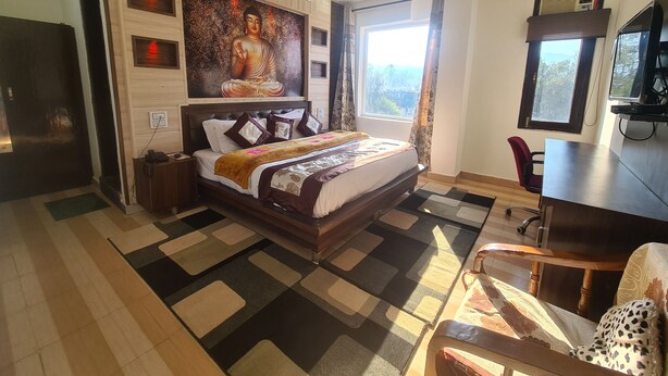 Habitación de hotel con una cama grande, un escritorio, una silla, un televisor y una ventana con vistas.