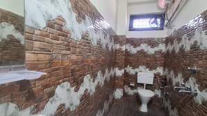 Un baño con diseño de pared de ladrillo, un inodoro, un lavamanos y una ventana.